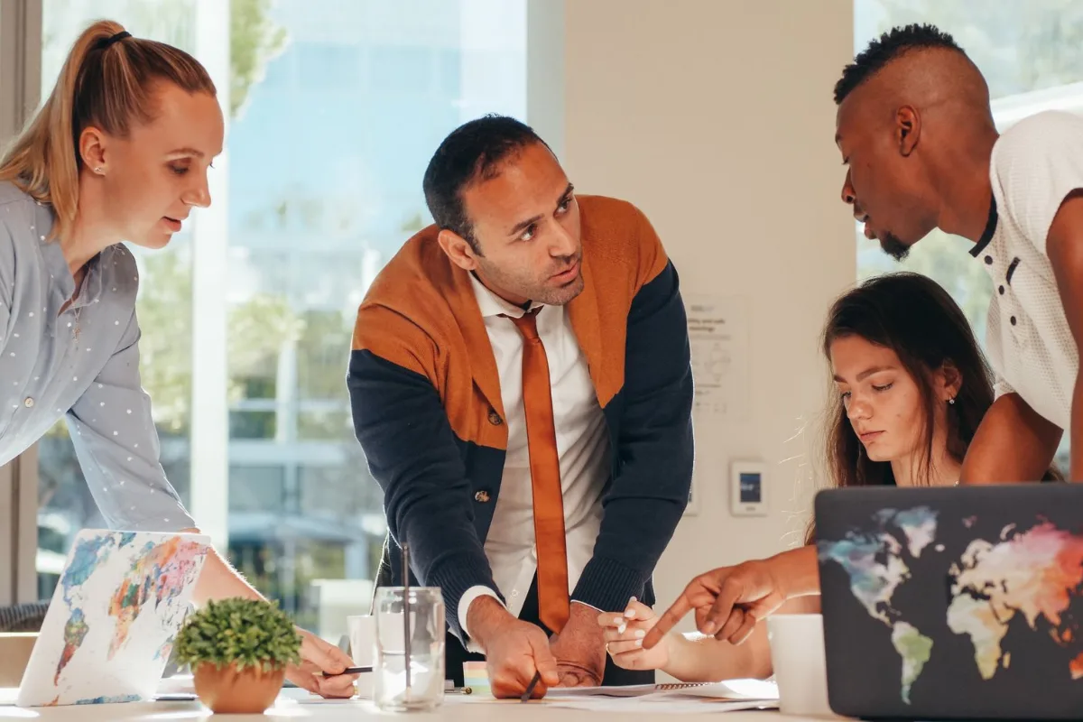 Equipe reunida em torno de um notebook analisando resultados de gestão