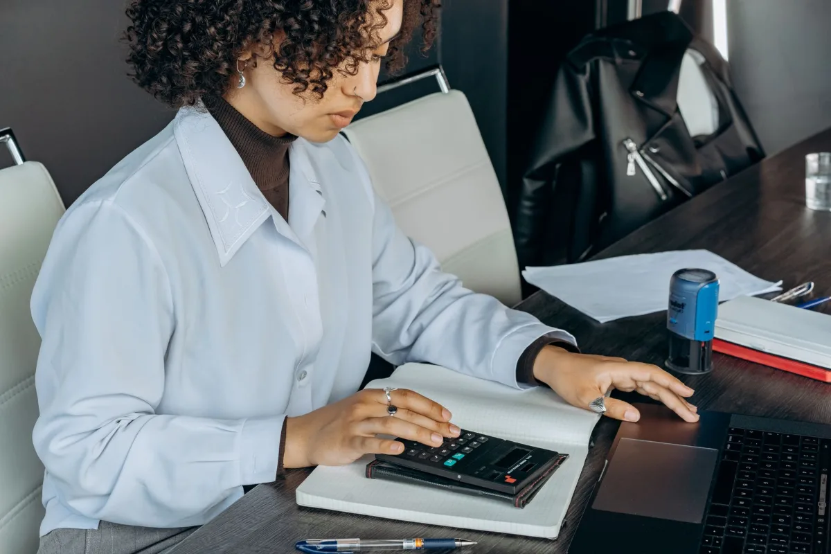 Profissional de contabilidade trabalhando com planilhas e calculadora no escritório